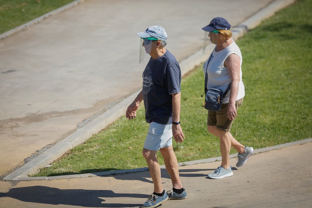 Dos personas con ropa veraniega y gorra pasean por el parque del Alamillo. En Sevilla (Andalucía, España), a 21 de mayo de 2020.