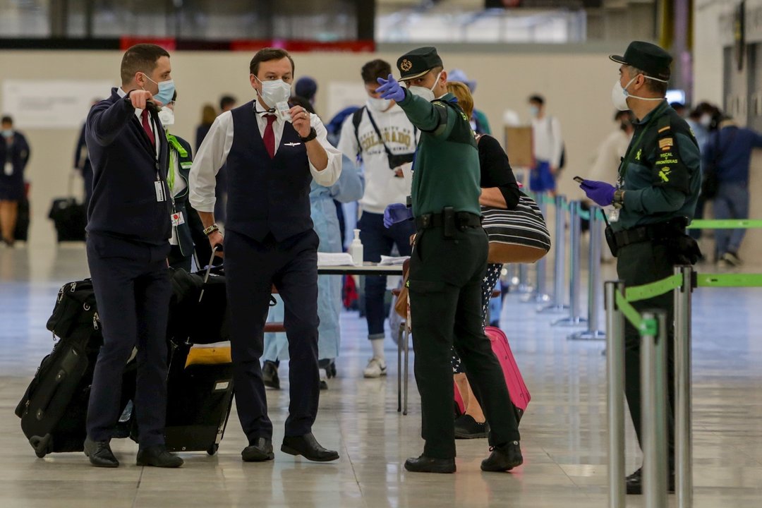 Agentes de la Guardia Civil ayudan a viajeros en la terminal 4 del Aeropuerto de Madrid en el día en el que entra en vigor la orden del Ministerio de Sanidad por la que todas las personas procedentes del extranjero deberán hacer una cuarentena de 14 días