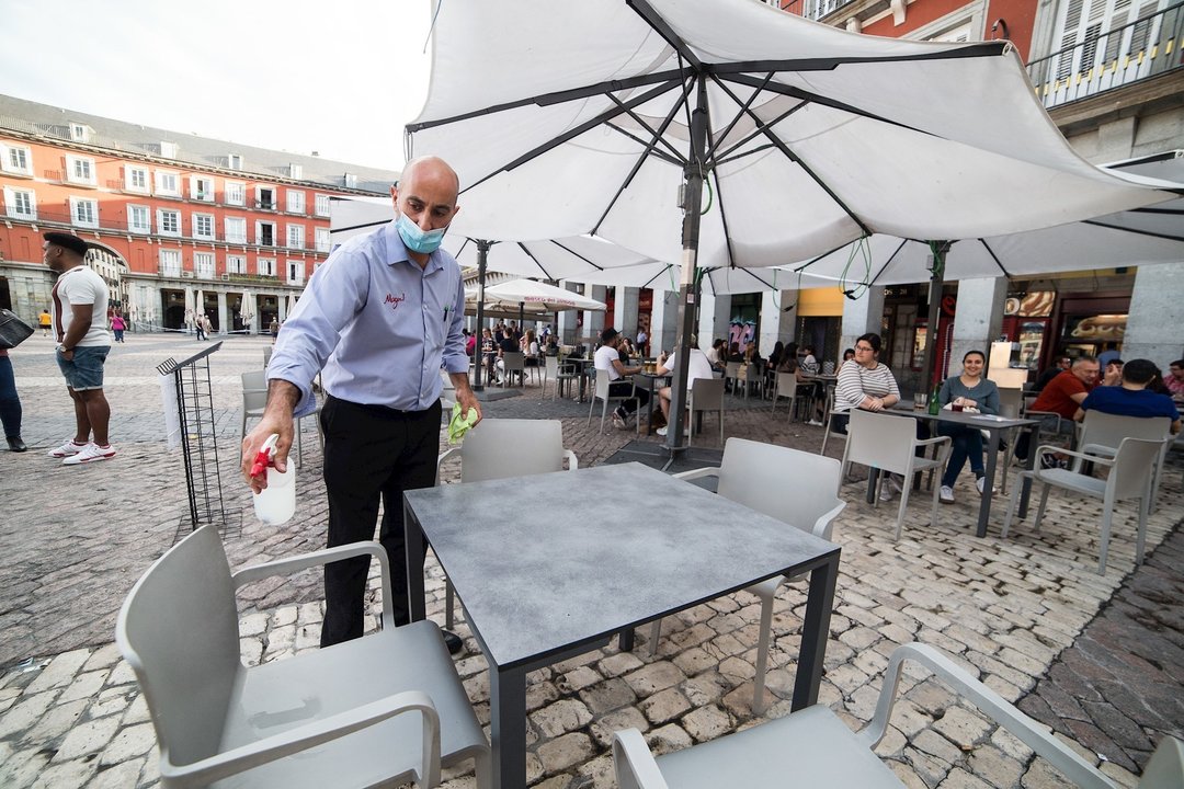 Un camarero desinfecta una mesa