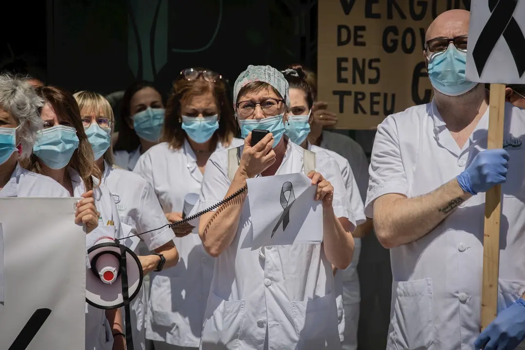 Una sanitaria habla por un meg&aacute;fono junto a otros compa&ntilde;eros de profesi&oacute;n a las puertas del Hospital Cl&iacute;nic de Barcelona donde sostienen pancartas y crespones negros para reivindicar contratos dignos y m&aacute;s personal. En Barcelona, a 27 de mayo de 2020.