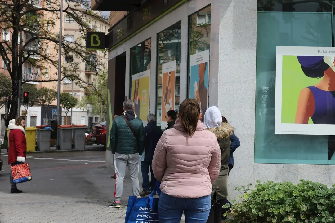 Personas en fila guardan su turno para entrar en una oficina de Bankia.
