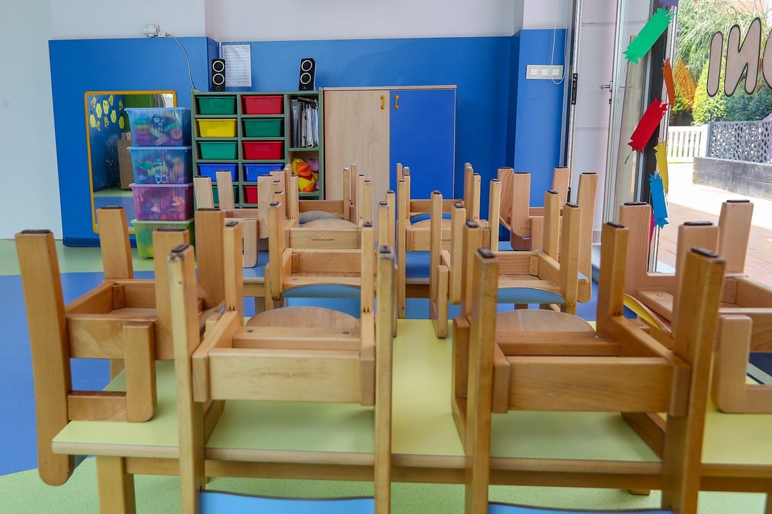 Mesas y sillas recogidas en un aula de un colegio.