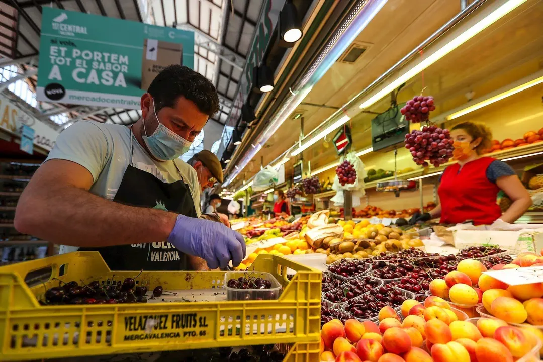 Un hombre trabaja colocando la fruta en una una fruter&iacute;a del Mercado Central de Valencia.