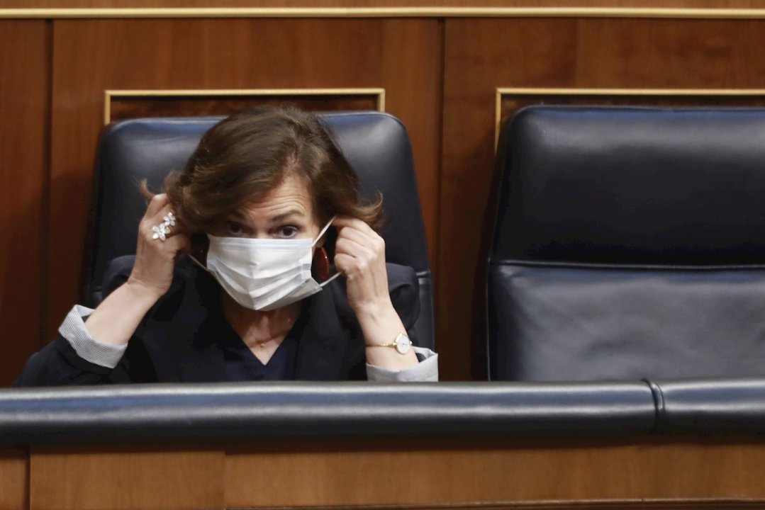 La vicepresidenta primera del Gobierno, Carmen Calvo, se coloca la mascarilla durante la sesión plenaria de control al Gobierno en el Congreso de los Diputados, donde la gestión durante la crisis sanitaria continúa en el punto de mira. En Madrid, (España)
