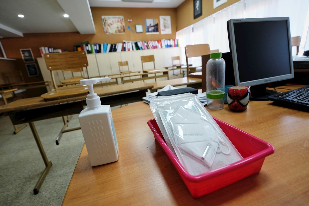 Mascarillas y gel desinfectante en la mesa del profesor de un aula. Archivo