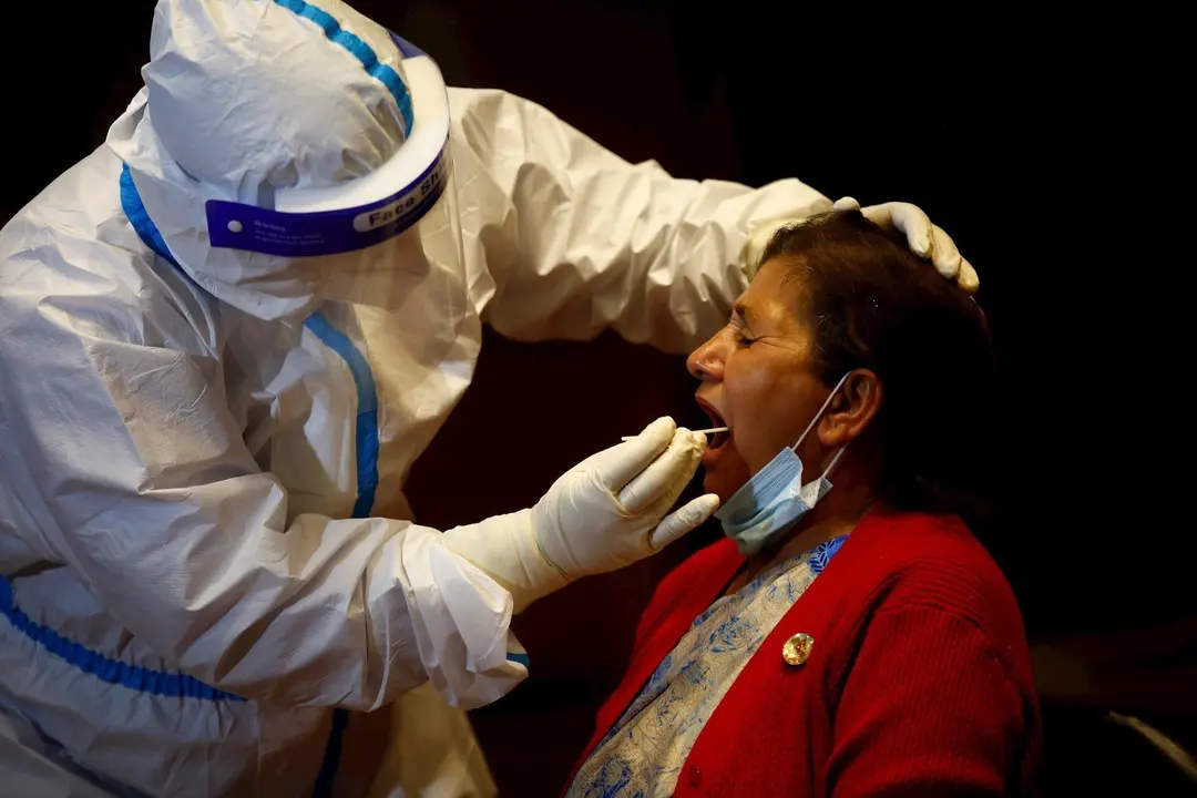 07 May 2020, Nepal, Kathmandu: A health worker takes a throat swab sample for the coronavirus PCR test from a woman, as the government is testing the members of National Assembly and House of Representatives for the novel coronavirus a day before the new 