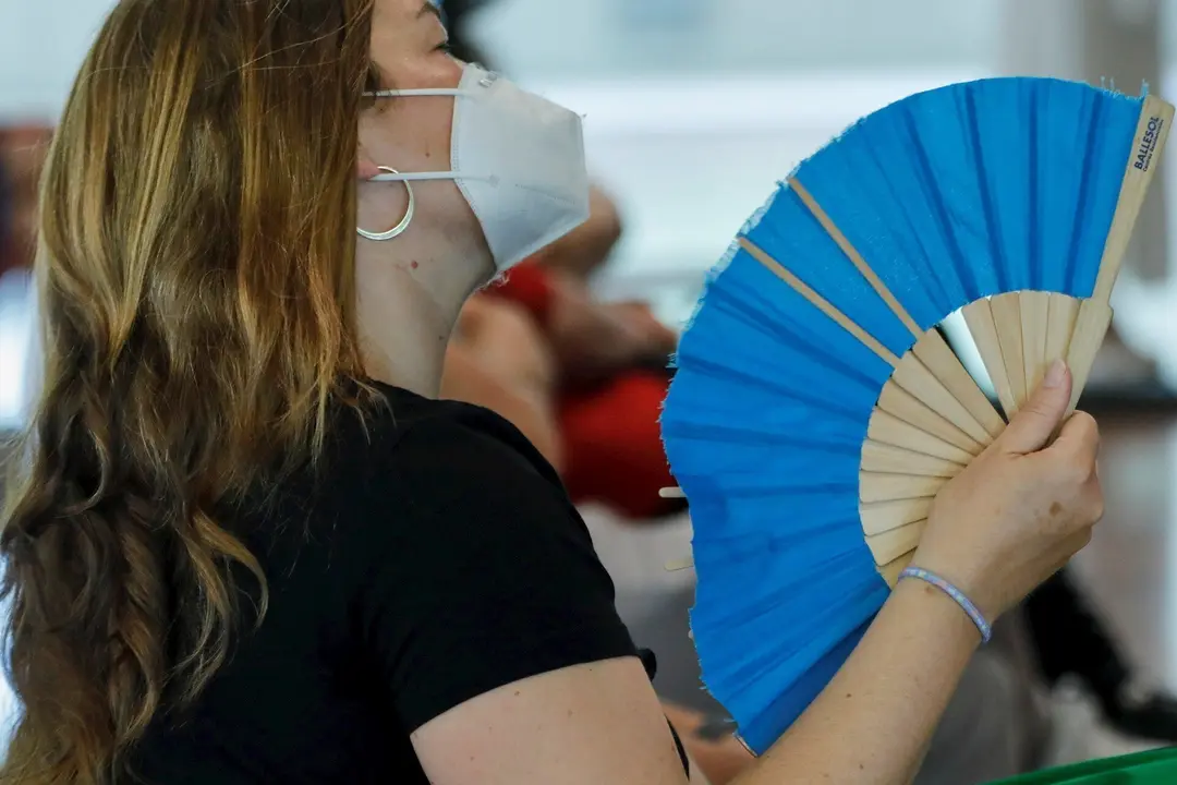 Una mujer con mascarilla se abanica en Madrid (Espa&ntilde;a), a 29 de junio de 2020. El calor pone desde este lunes en aviso a una quincena de provincias de Andaluc&iacute;a, Castilla y Le&oacute;n, Castilla-La Mancha, Extremadura y Madrid, por temperaturas m&aacute;ximas que van d