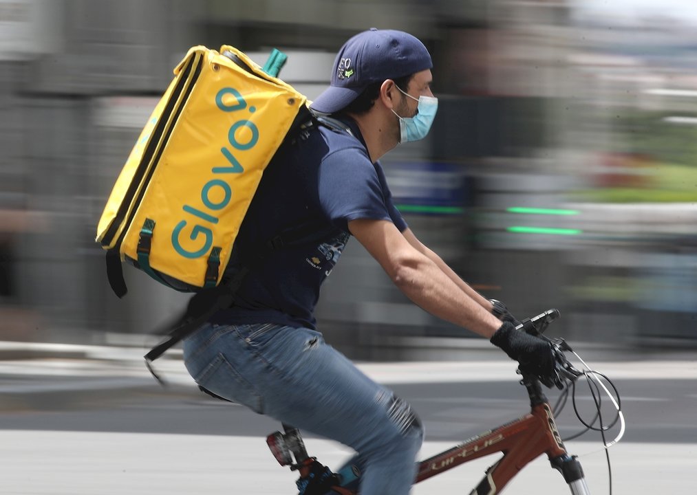 Un repartidor de Glovo monta una bicicleta durante su jornada laboral.