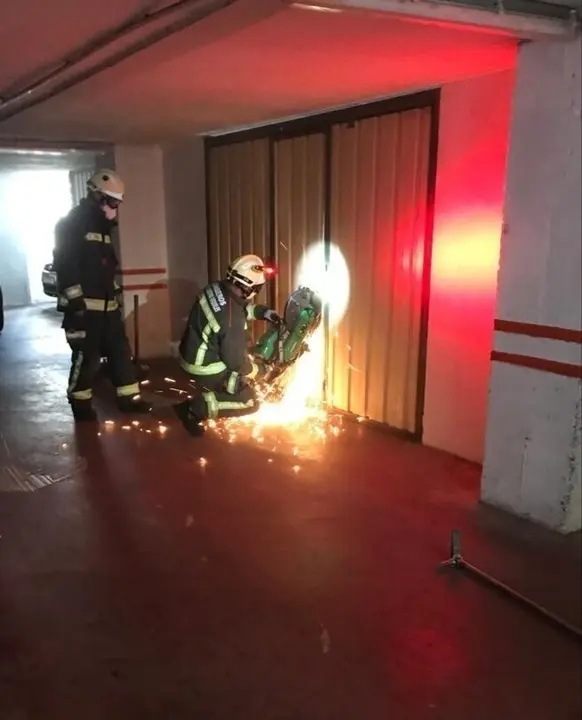 Bomberos abren la puerta del garaje donde se ha encontrado al hombre fallecido