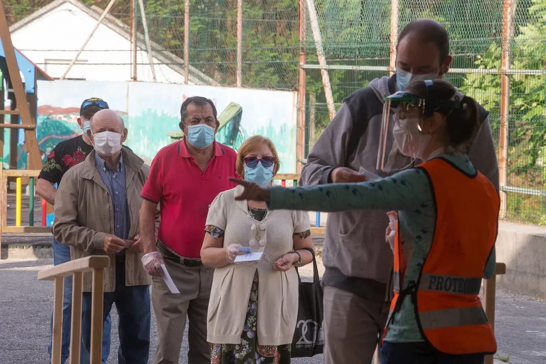 Varias personas protegidas con mascarillas hacen cola para poder votar en las elecciones auton&oacute;micas de Galicia