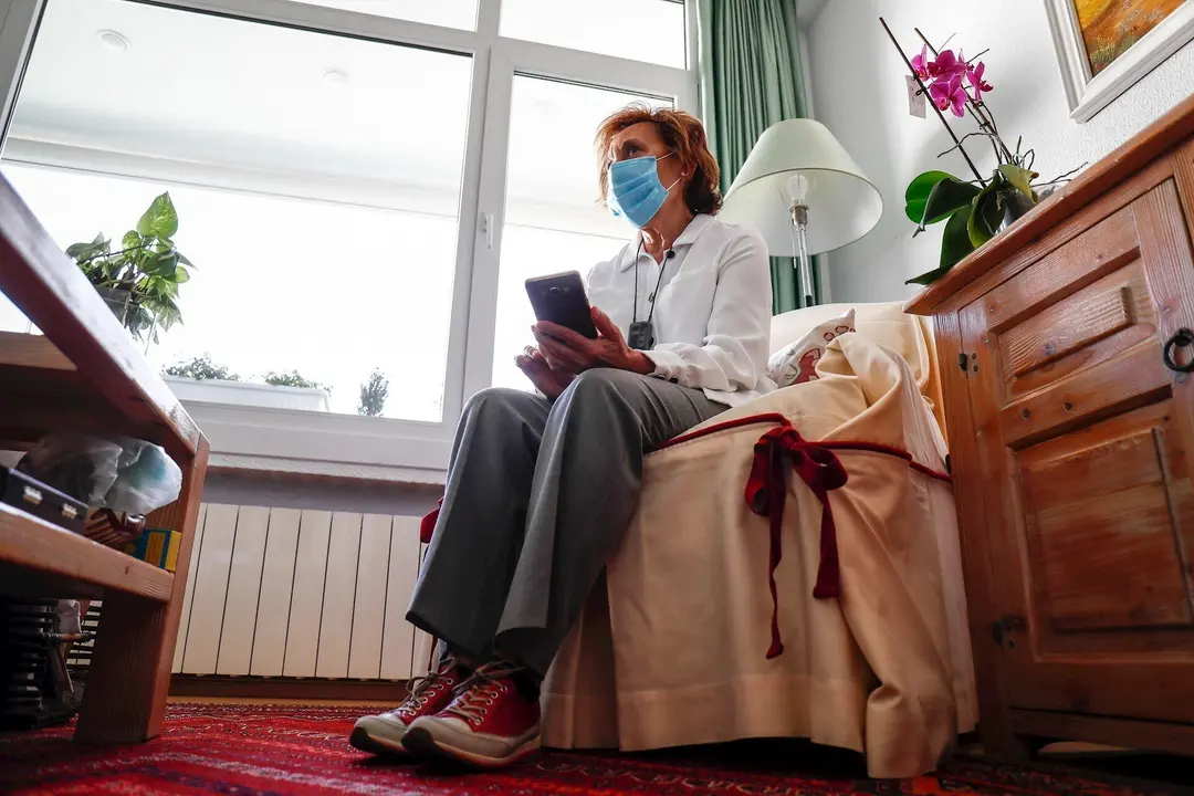 Araceli, usuaria de aud&iacute;fonos intracanales y miembro de FIAPAS (Confederaci&oacute;n Espa&ntilde;ola de Familias de Personas Sordas), observa su tel&eacute;fono m&oacute;vil desde el sal&oacute;n de su domicilio, durante la fase 2 de la desescalada.