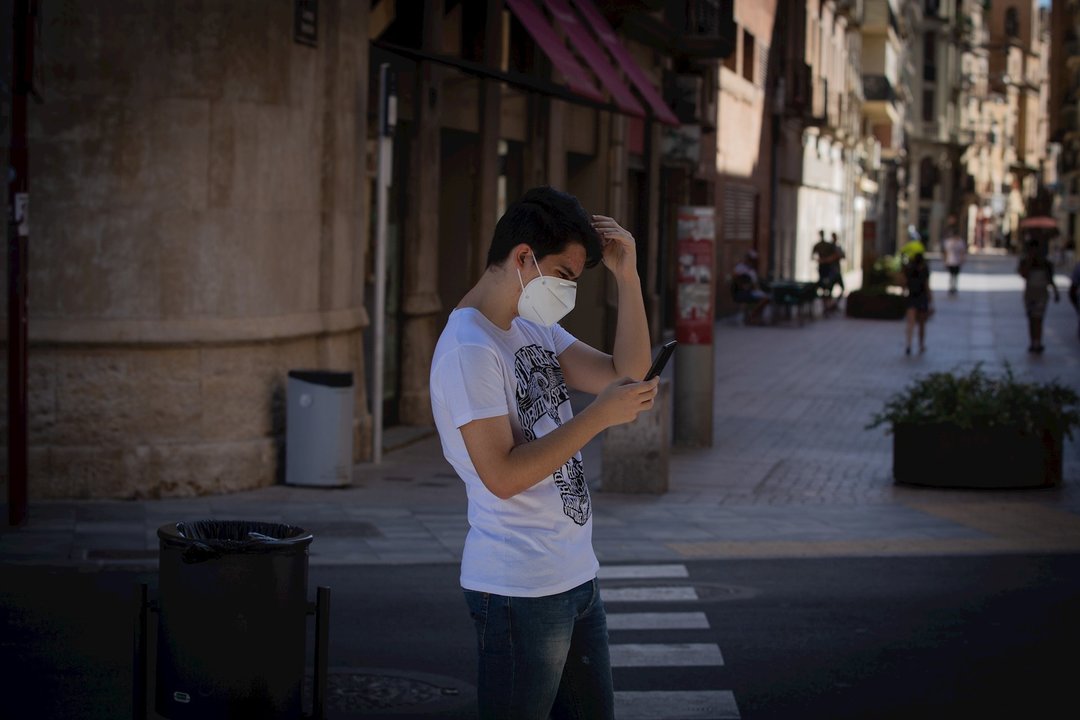 Un joven protegido con mascarilla camina por una calle del centro de Lleida, capital de la comarca del Segrià, en Lleida.