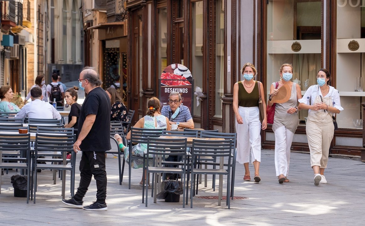 Tres ciudadanas pasean con mascarillas y abanico por el fuerte calor en el primer día de uso obligatorio de mascarillas en Sevilla