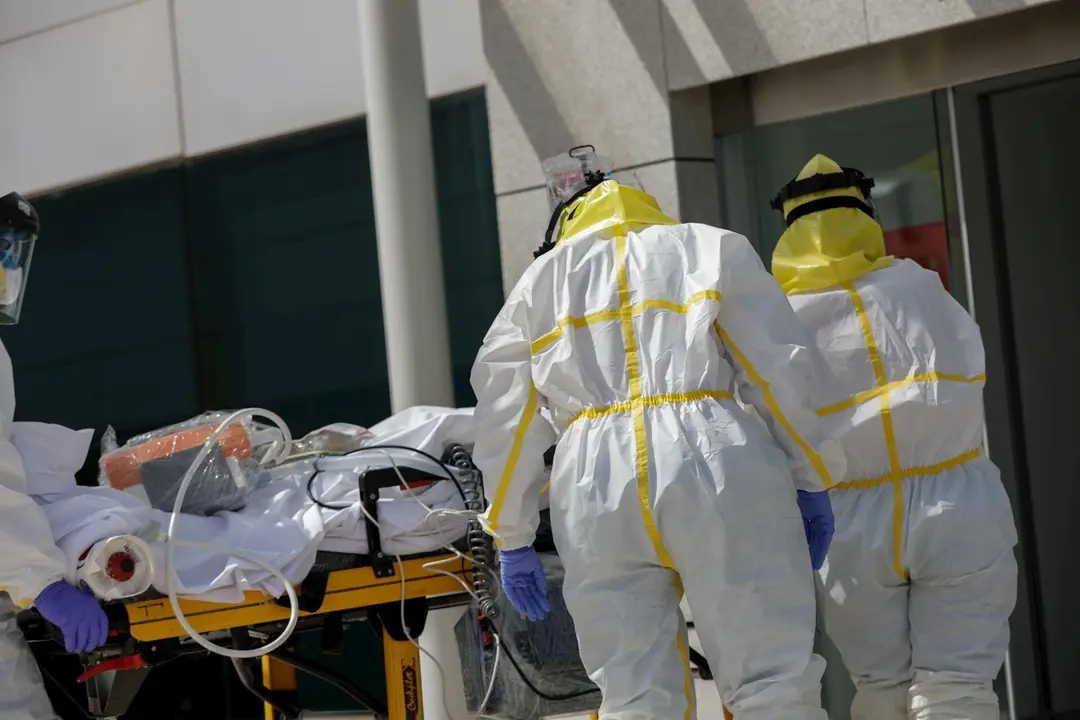 Varios sanitarios trasladan a un paciente desde el interior de la unidad m&oacute;vil del SUMMA hasta la entrada del Hospital Puerta de Hierro tras haberle trasladado anteriormente desde la UVI del hospital temporal de IFEMA, durante un d&iacute;a de trabajo del Servic