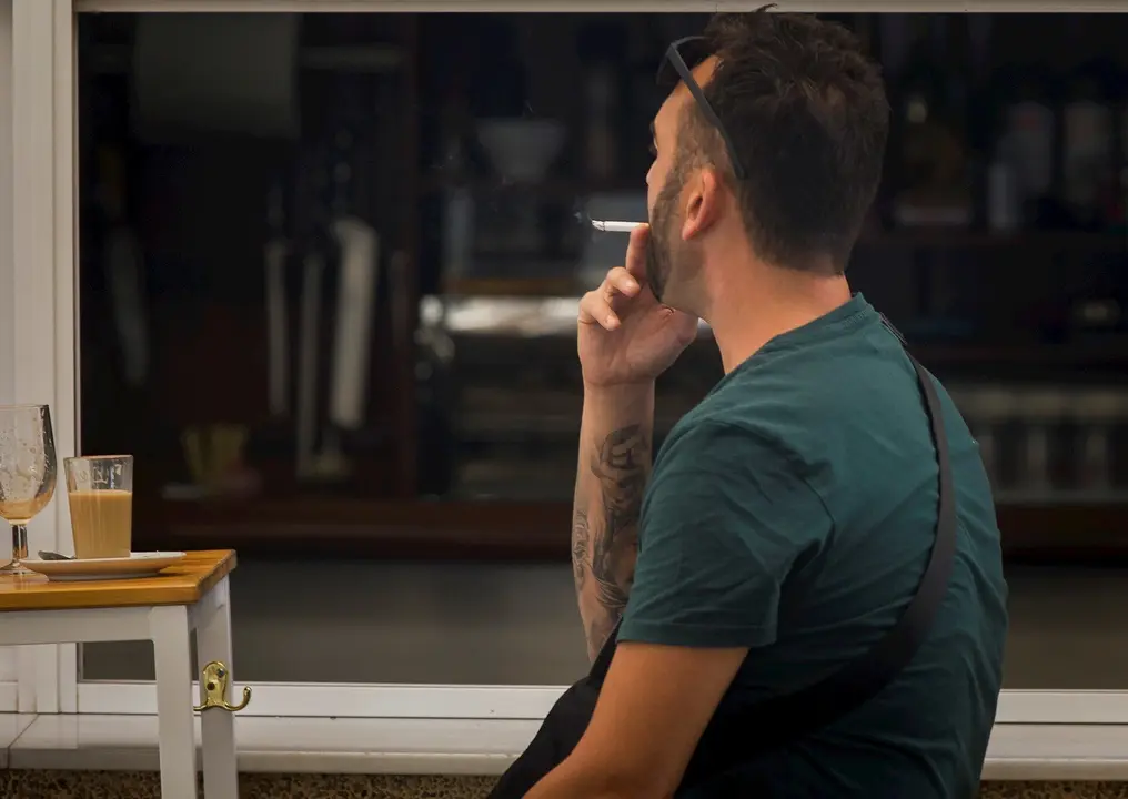 Una persona fuma en una terraza durante el primer d&iacute;a de la prohibici&oacute;n de realizarlo en la v&iacute;a p&uacute;blica en Andaluc&iacute;a. En Sevilla, (Andaluc&iacute;a, Espa&ntilde;a), a 17 de agosto de 2020.