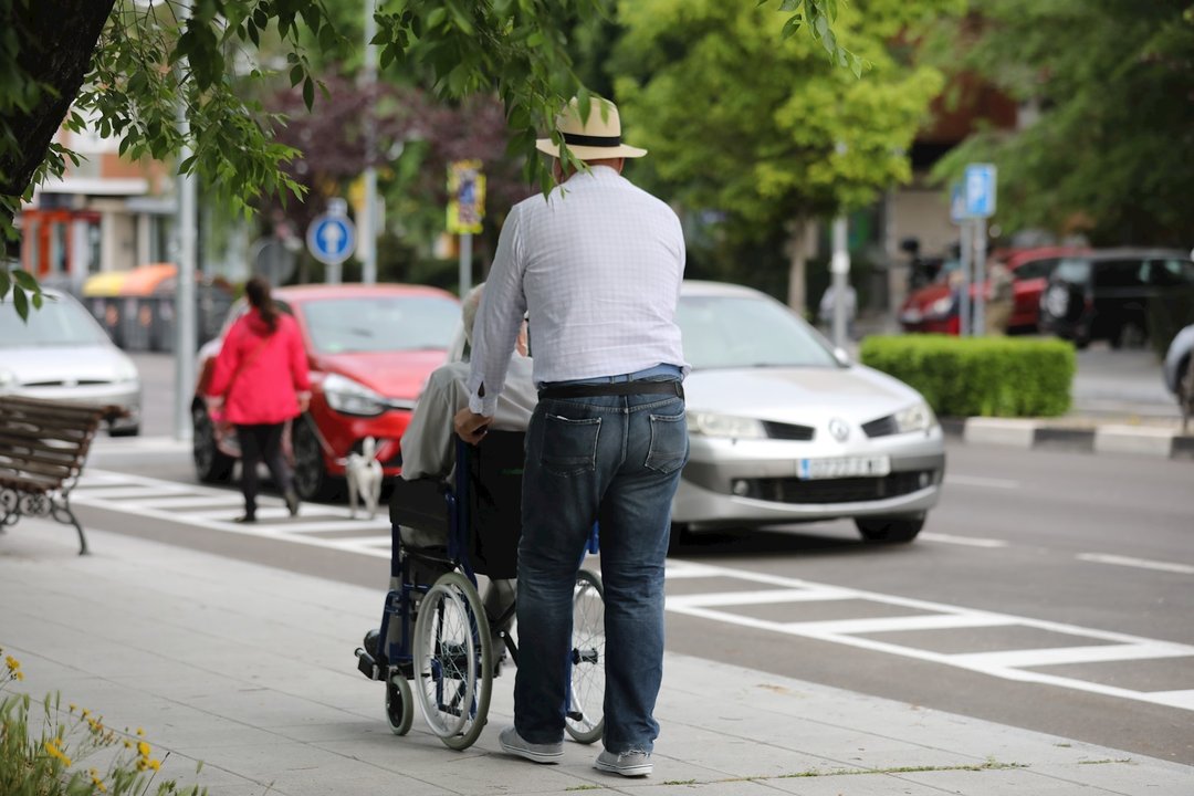 Un hombre pasea a una persona de edad avanzada en silla de ruedas. En Madrid, (España), a 7 de mayo de 2020.