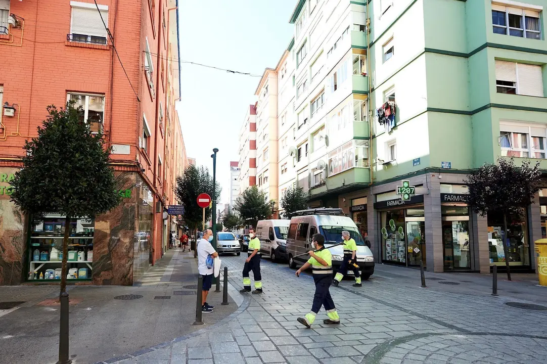 Empleados de la limpieza caminan por las calles del barrio La Inmobiliaria de Torrelavega