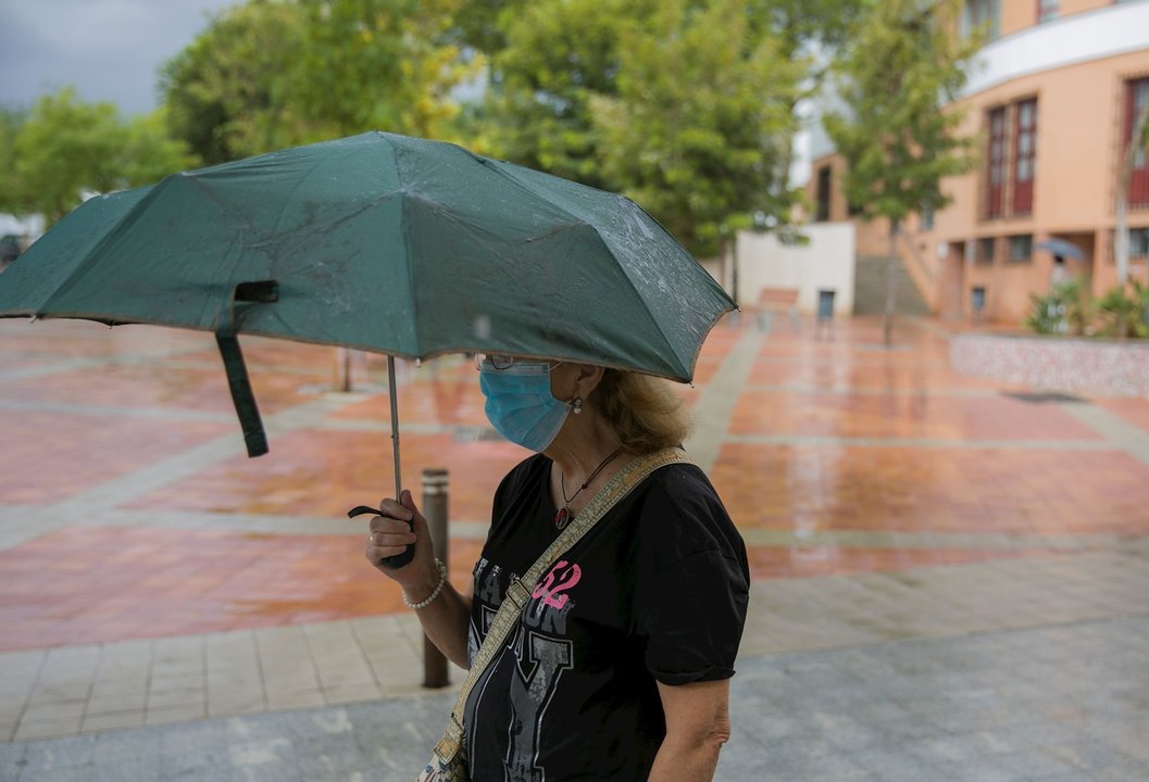 Una mujer se protege de la lluvia bajo su paraguas en Tomares (Sevilla, Andalucía, España), a 18 de septiembre de 2020.