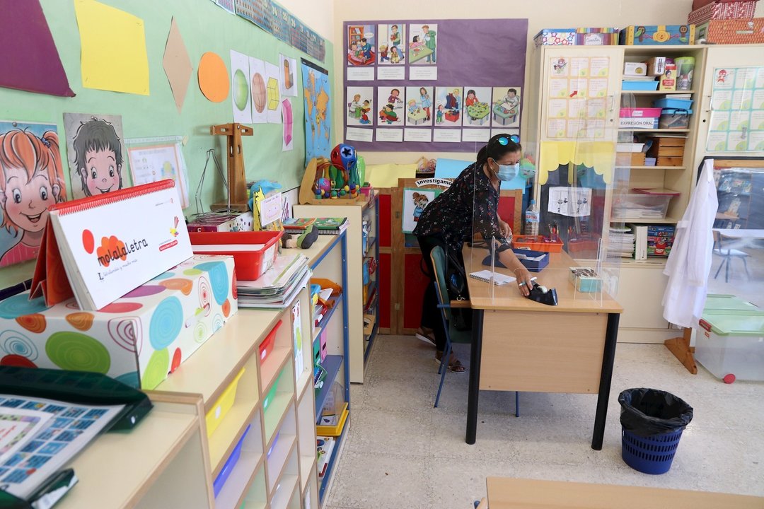 Una profesora prepara la documentación del inicio del curso escolar entre dos mampáras en un colegio en Málaga a 9 de septiembre 2020
