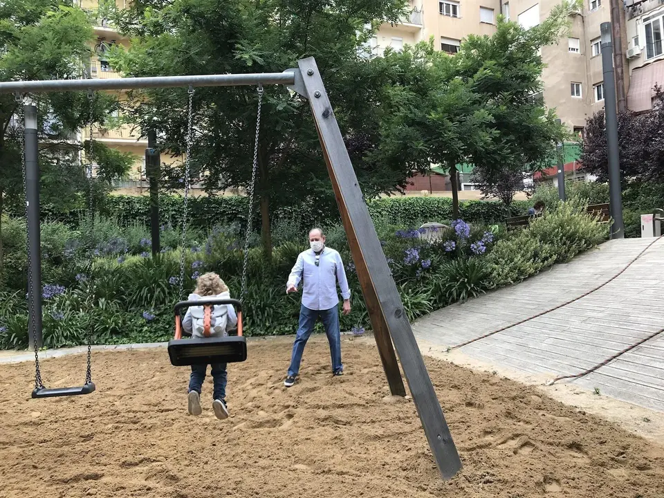 Una ni&ntilde;a y su abuelo juegan en los columpios