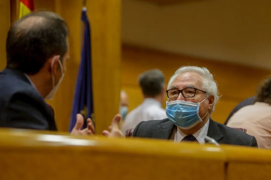 El ministro de Universidades, Manuel Castells, con mascarilla, conversa con un senador poco antes de comparecer en el Senado en la comisi&oacute;n de su departamento, el pasado 22 de junio, en Madrid
