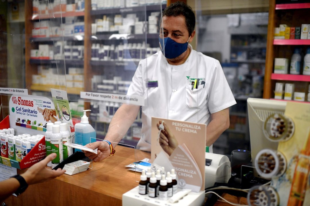 Un farmacéutico entrega a un cliente una de las mascarillas KN95 que ha recibido en su farmacia, en Madrid (España), a 30 de septiembre. Hoy era la fecha límite fijada por el Gobierno para dejar de comercializar equipos de protección individual (EPI) sin 