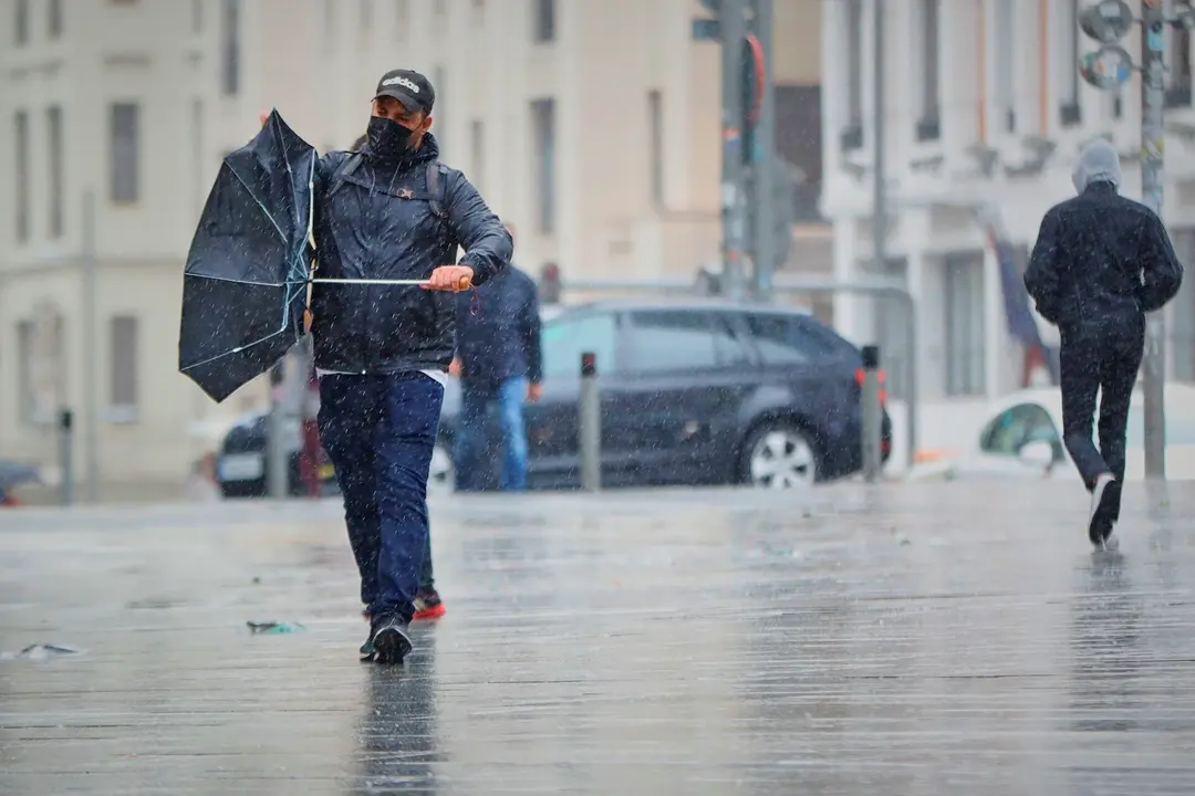 Transe&uacute;ntes pasean por el centro de la capital en una jornada marcada por las lluvias y la bajada de temperaturas, en Madrid.