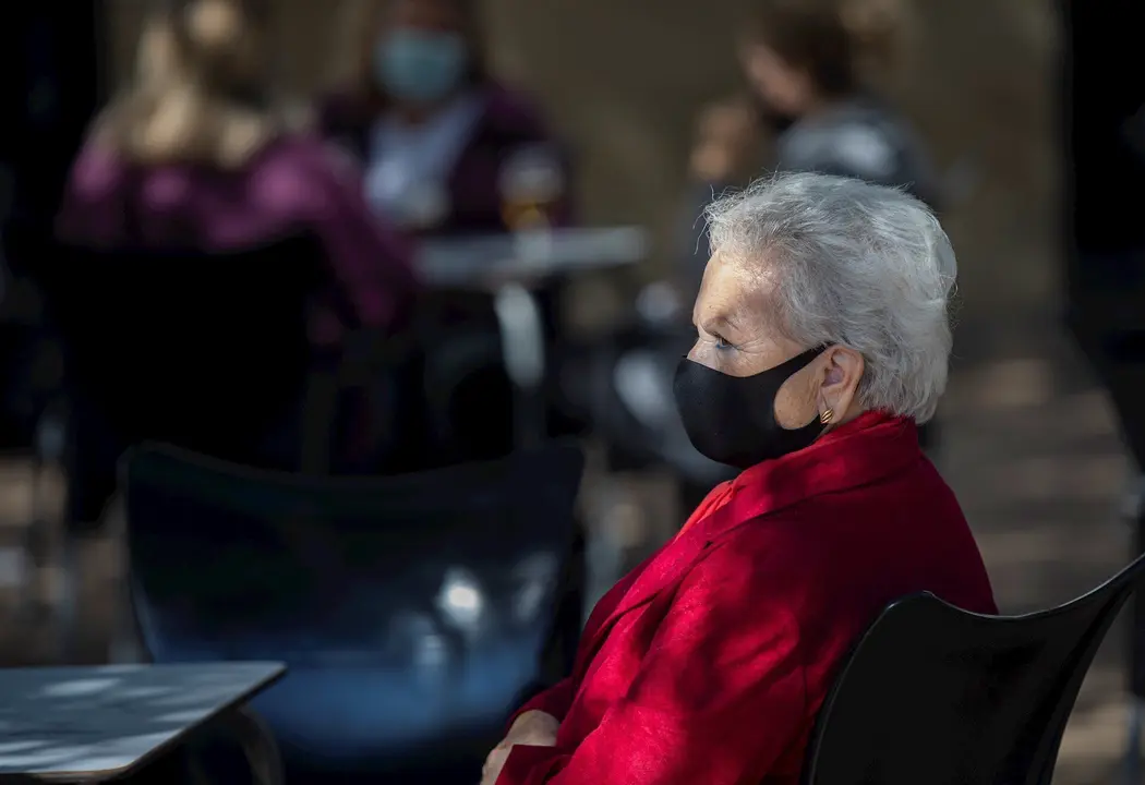 Una mujer mayor con mascarilla en la terraza de un bar. En Sevilla (Andaluc&iacute;a, Espa&ntilde;a), a 23 octubre de 2020.