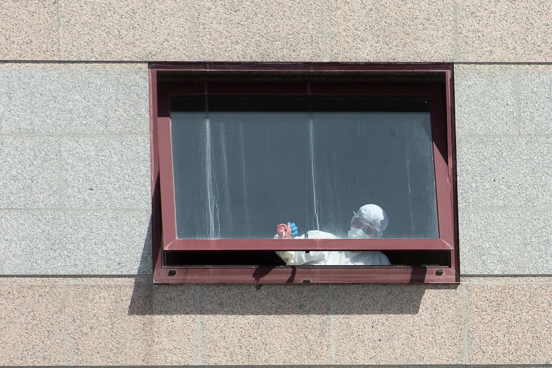 Un trabajador protegido es visto por uno de los cristales de la  residencia de mayores DomusVi de Outeiro de Rei en Lugo, Galicia (Espa&ntilde;a), a 8 de septiembre de 2020. 