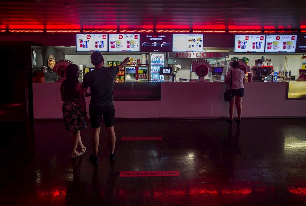 Dos personas eligen un menú de palomitas y refresco en el primer fin de semana con estrenos en las salas de cine, el pasado mes de junio