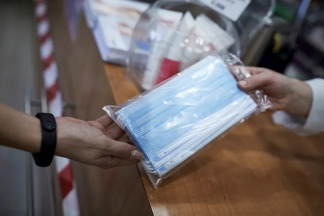 Una farmac&eacute;utica ense&ntilde;a a un cliente un paquete de mascarillas en la farmacia situada en la calle Tuc&aacute;n, 7, en el distrito de Carabanchel, Madrid (Espa&ntilde;a), a 11 de noviembre de 2020.