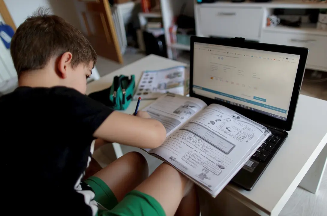 Un alumno de primaria hace los deberes de la asignatura de Ingl&eacute;s con varios libros y un ordenador