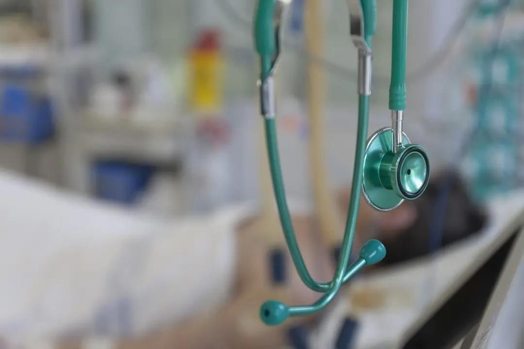 Green stethoscope, on background patient  connected to medical ventilator in ICU in hospital, a place where can be treated patients with pneumonia caused by coronavirus covid-19. (Green stethoscope, on background patient  connected to medical ventilat