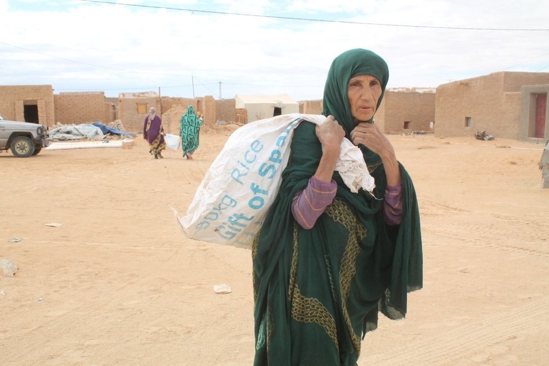 Una refugiada saharaui carga un saco con comida del Programa Mundial de Alimentos