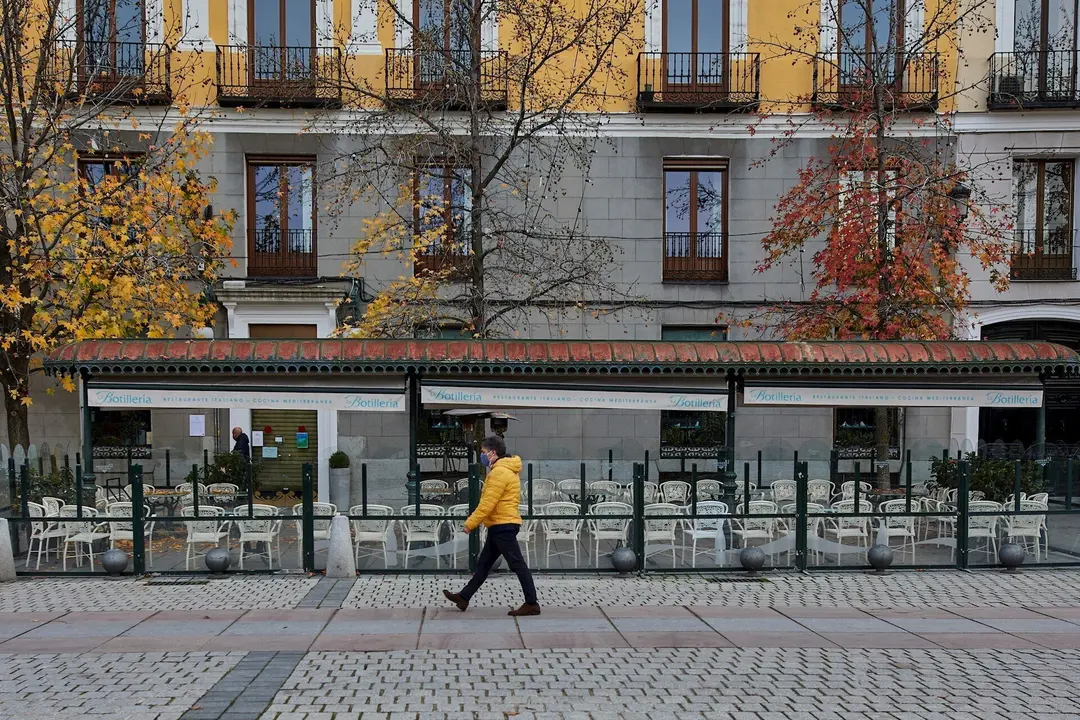 Una persona pasea al lado de una mampara instalada en un restaurante de la Plaza de Oriente, en Madrid (Espa&ntilde;a), a 12 de noviembre de 2020.