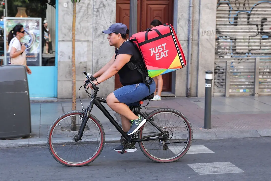 Fotograf&iacute;a de un repartidor de la empresa de reparto Just Eat transitando en bicicleta por una calle del centro de Madrid.