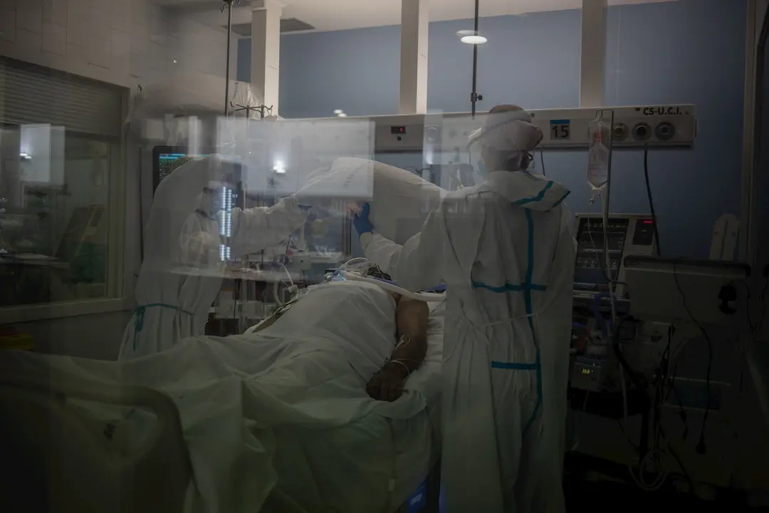 Trabajadores sanitarios protegidos atienden a un paciente en la UCI
