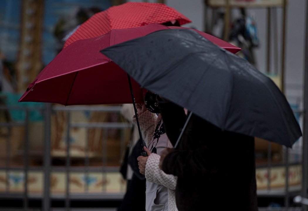 Peatones con paraguas. Imagen de archivo