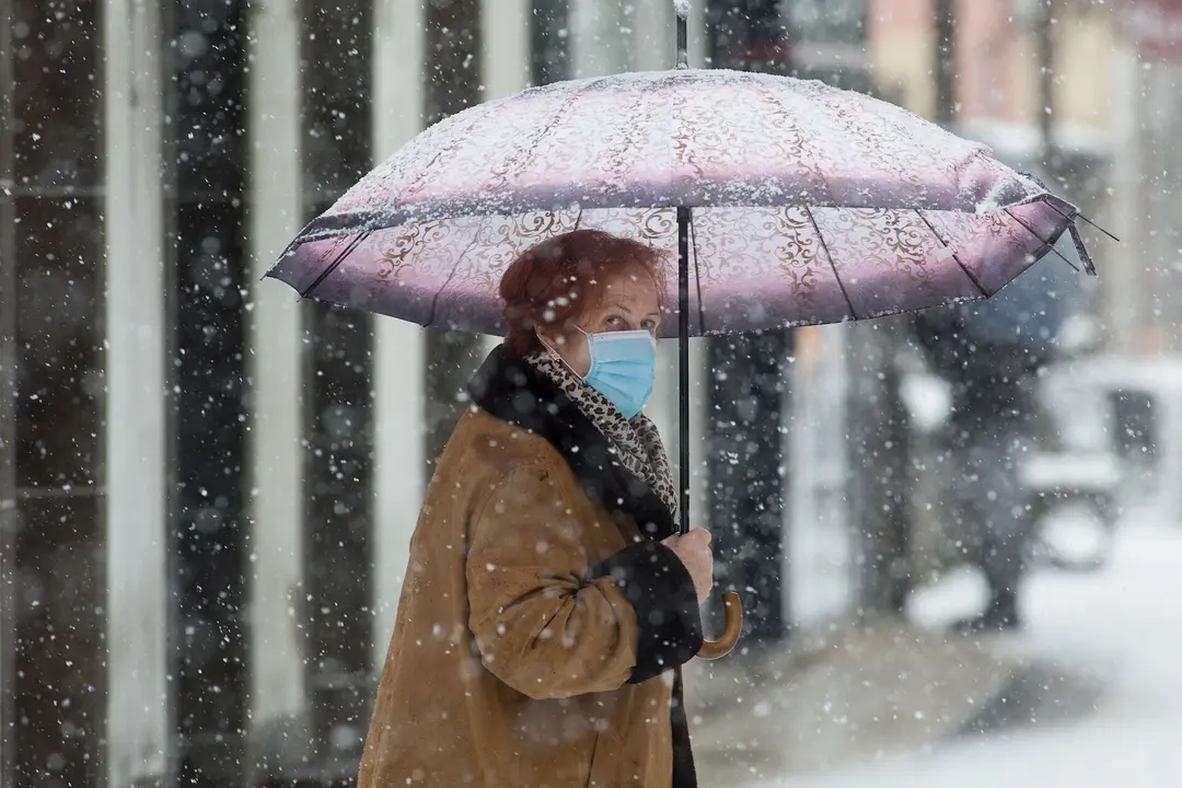 Una mujer se cubre de la nieve con un paraguas en Becerrea, en Lugo, Galicia (Espa&ntilde;a), a 4 de diciembre de 2020. Hoy se ha producido la primera gran nevada del oto&ntilde;o en la monta&ntilde;a lucense. La intensa nevada que est&aacute; cayendo sobre el centro de la provincia