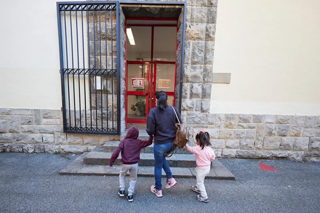 Una madre lleva a sus hijos al Colegio.