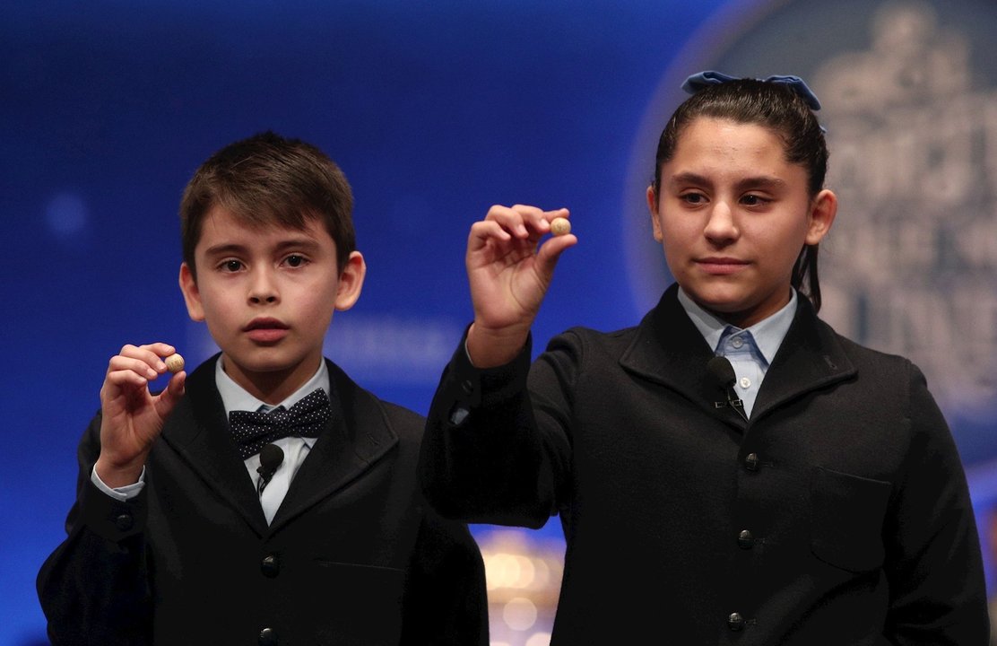 Dos de los niños de la residencia de San Ildefonso, posan con las bolas correspondientes al Segudo Premio de la Lotería de Navidad, con el nº 10.989, el cual ha salido durante el canto de la sexta tabla del Sorteo Extraordinario de la Lotería de Navidad 2