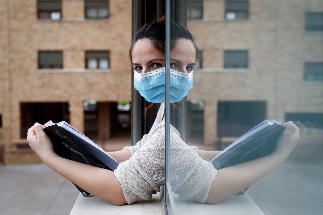 Una mujer con una mascarilla lee asomada a la ventana de su casa cuando queda tan solo una semana para que niños y preadolescentes puedan salir a la calle durante el confinamiento por el coronavirus, en Valdemoro/Madrid (España) a 20 de abril de 2020.
