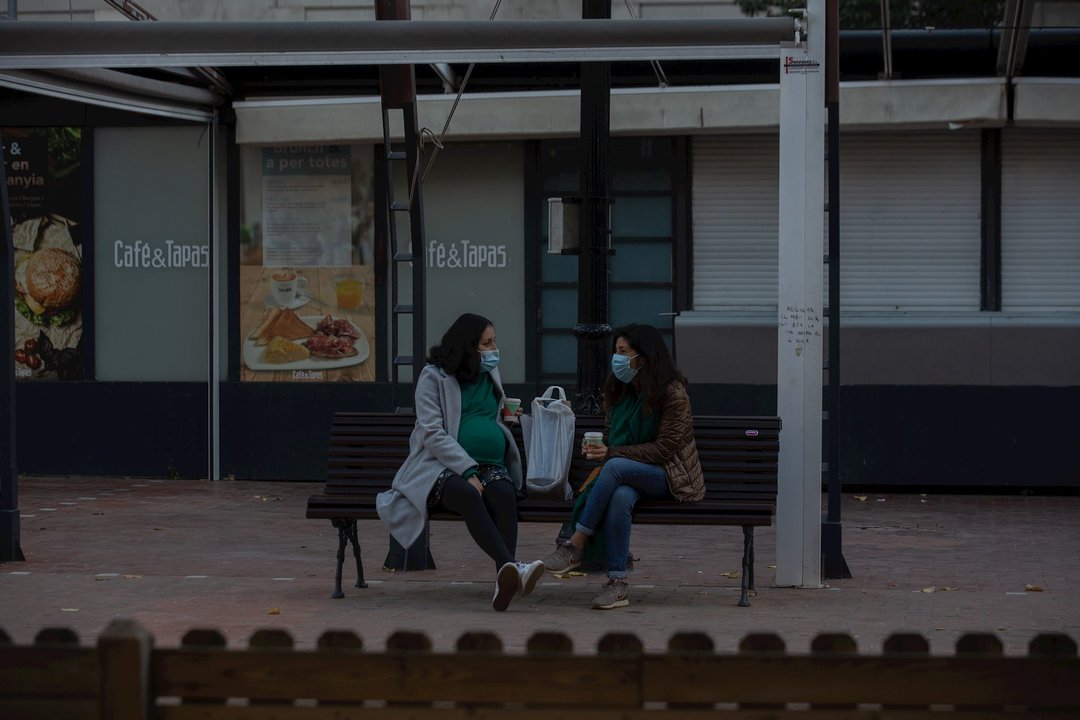 Dos mujeres charlan sentadas en un banco, en Barcelona, Catalunya (España), a 21 de diciembre de 2020. Debido al incremento de la curva de la pandemia en Catalunya y ante "la posible llegada de una tercera ola que incremente el nivel de presión sobre los 