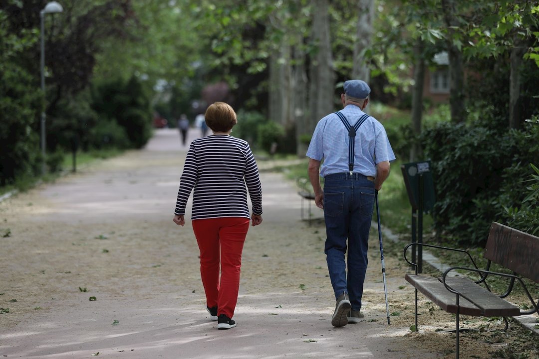Una mujer y un hombre de edad avanzada con bastón dando un paseo.