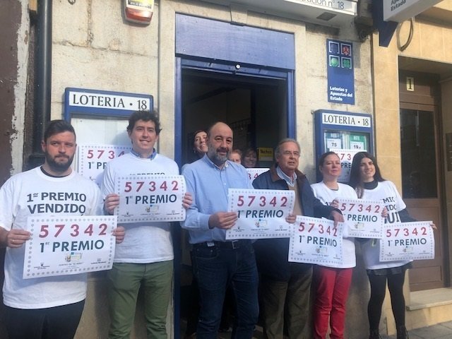 El propietario de la Administración de Lotería 18 de Santander, Manuel Puente (en el centro con camisa azul), con el número del primer premio del Sorteo del Niño, del que ha vendido un décimo