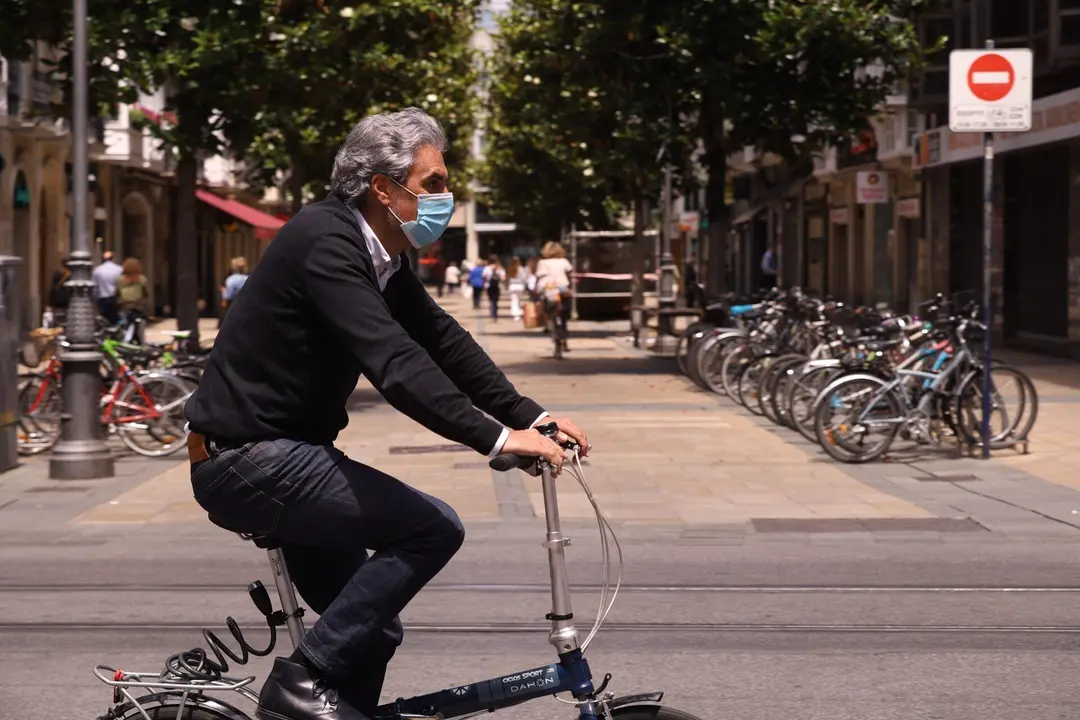 Un hombre pasea en bicicleta con mascarilla por una c&eacute;ntrica calle de Vitoria-Gasteiz, &Aacute;lava, Pa&iacute;s Vasco (Espa&ntilde;a).