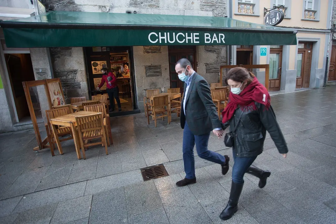 Dos personas pasan frente a una terraza en en Lugo, tras el levantamiento del cierre perimetral de la ciudad, en Lugo, Galicia (Espa&ntilde;a), a 30 de diciembre de 2020.  Lugo y Ourense ser&aacute;n las dos &uacute;nicas urbes gallegas sin cierre perimetral en Fin de A&ntilde;o, de