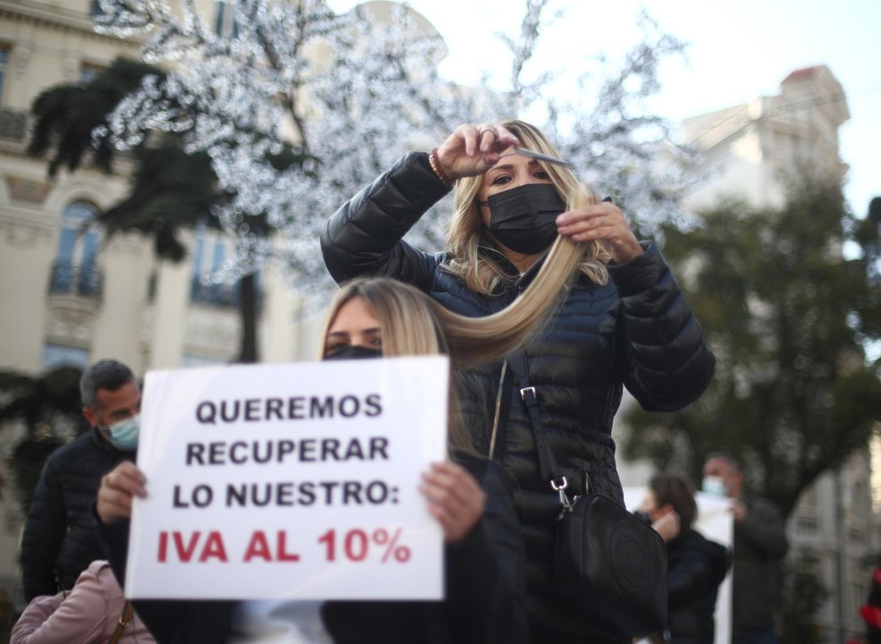 Una peluquera corta el pelo a una mujer durante una concentración frente al Congreso de los Diputados, en Madrid (España) 