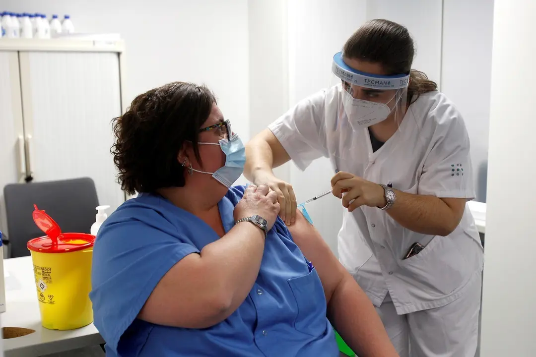 Una enfermera administra la vacuna Pfizer-BioNtech contra el COVID-19 a una profesional sanitaria en el Hospital Son Espases de Palma de Mallorca, en Mallorca, Islas Baleares (Espa&ntilde;a), a 13 de enero de 2021. Baleares ha arrancado este mi&eacute;rcoles la vacunac