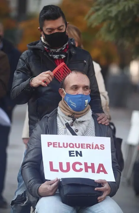 Un peluquero peina a un hombre durante una concentraci&oacute;n frente al Congreso de los Diputados